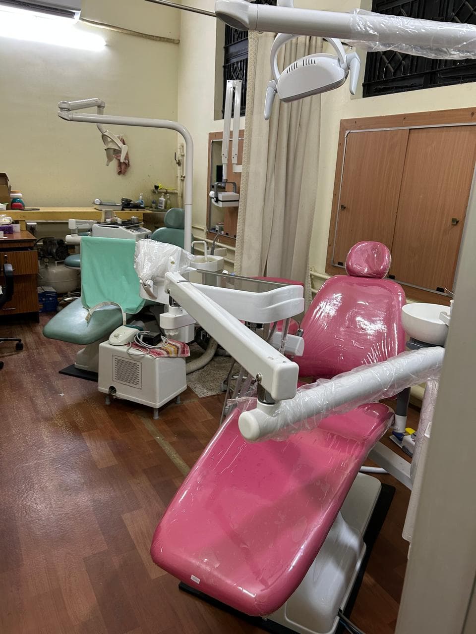 Two modern dental chairs – pink and green – in the clinic